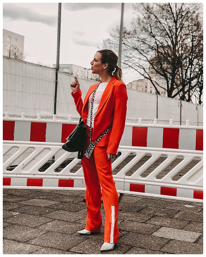 Frau im roten Hosenanzug vor einer Baustelle während der Fashion Week Berlin 