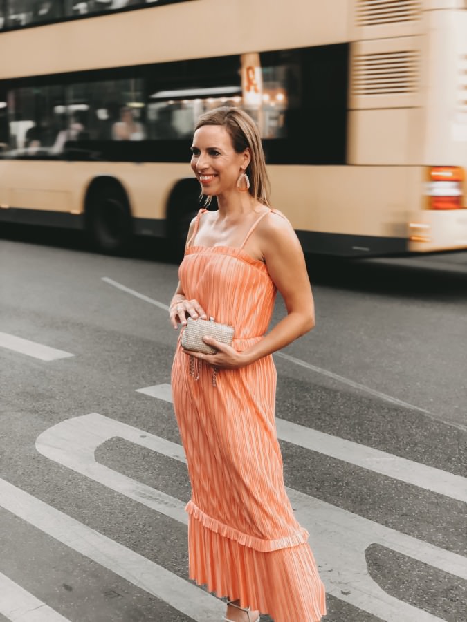 Fashion Week 2019 Plissee Kleid in Koralle mit silberfarbener Clutch